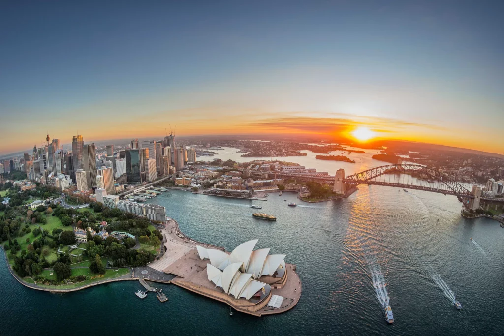 Aerial of Sydney city at sunset, including the Harbour Bridge and Opera House
