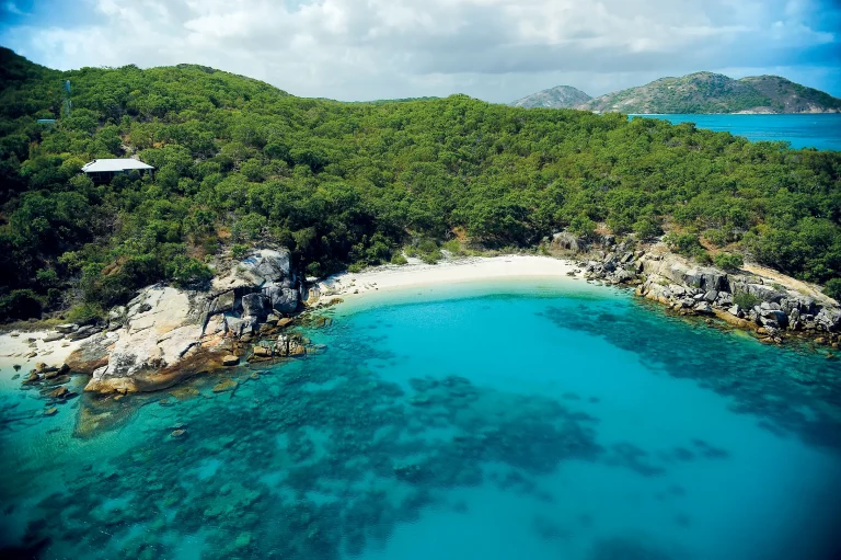 Landscape of Lizard Island beachfront showing white sand beaches, clear blue waters, and green tropical forest