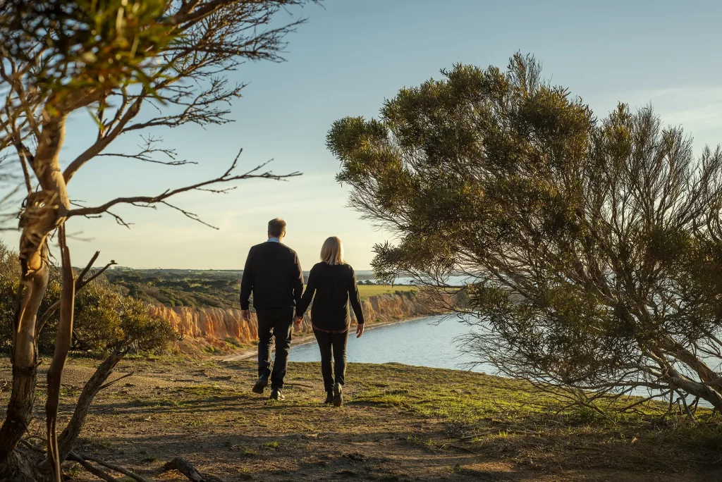 Couple walking hand-in-hand in late afternoon light in bush near Nepean Bay, Kangaroo Island