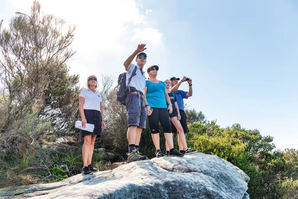 Guides leading a small group of guests through Sydney’s Northern Beaches on a rocky outcrop