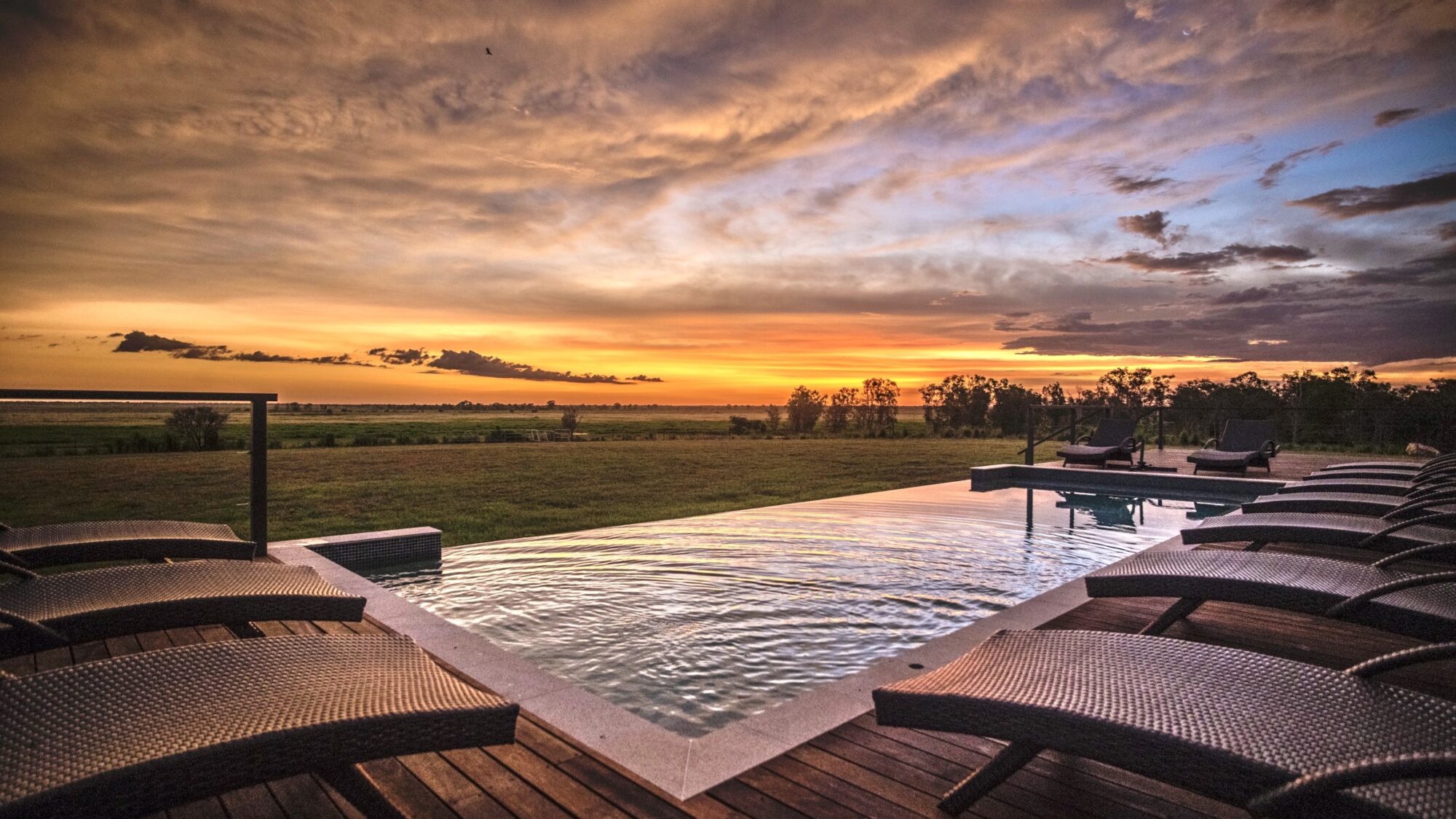 a pool with a deck and chairs in the back