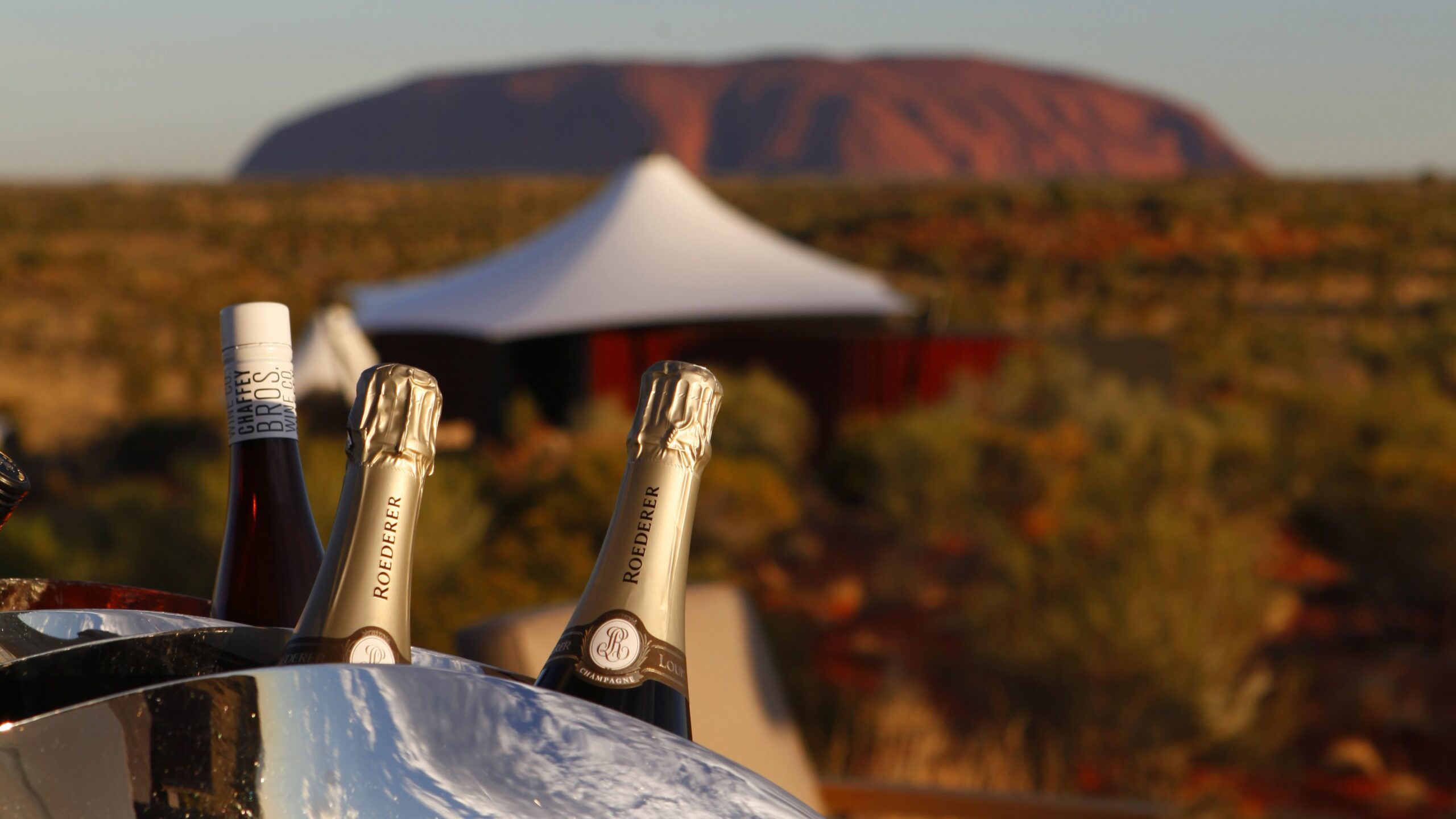 Bottles of champagne in a wine cooler overlooking Uluru in the Northern Territory