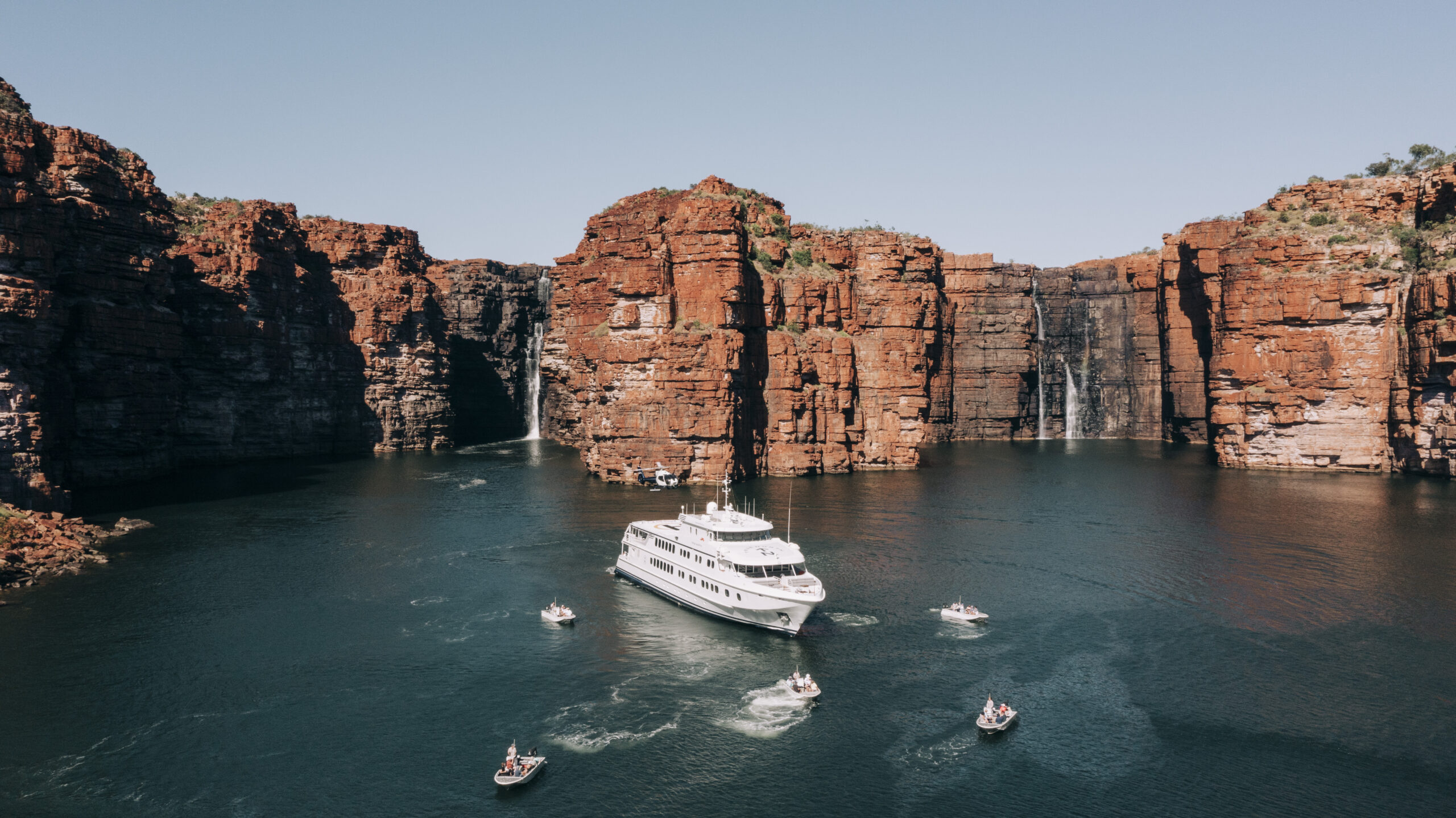 Landscape of the True North vessel and full fleet of tenders and helicopter at King George Falls, Kimberley, Western Australia