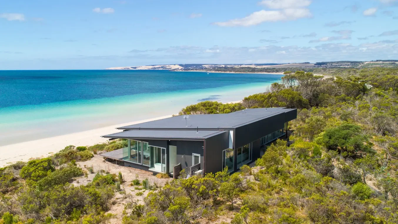 Exterior of private home One Kangaroo Island nestled amongst bush overlooking a white sand beach