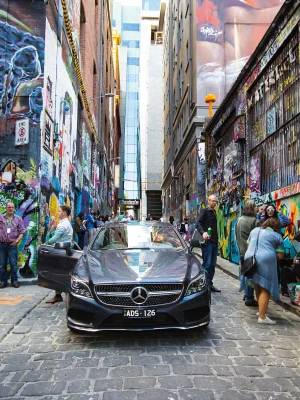 Luxury Mercedes vehicle parked in street-art-lined Hosier Lane.