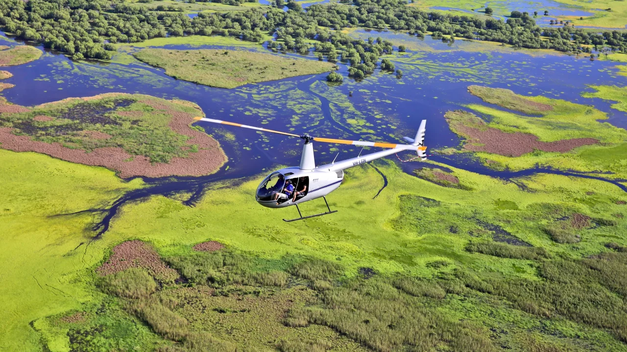 Helicopter flying above lush green floodplains in the Northern Territory’s Top End