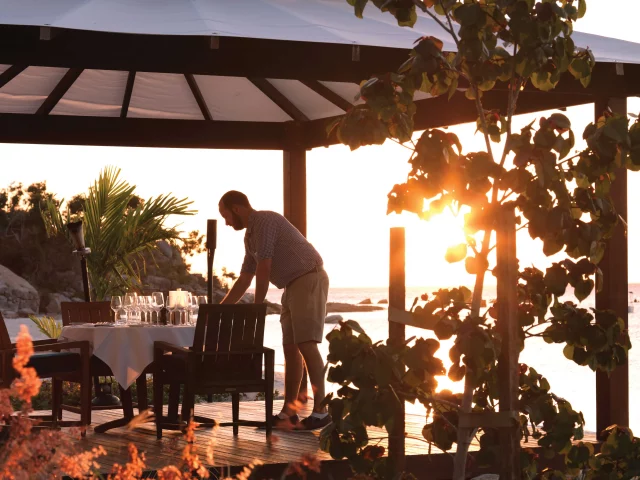 Staff member setting up a degustation dinner in a private outside pavilion.
