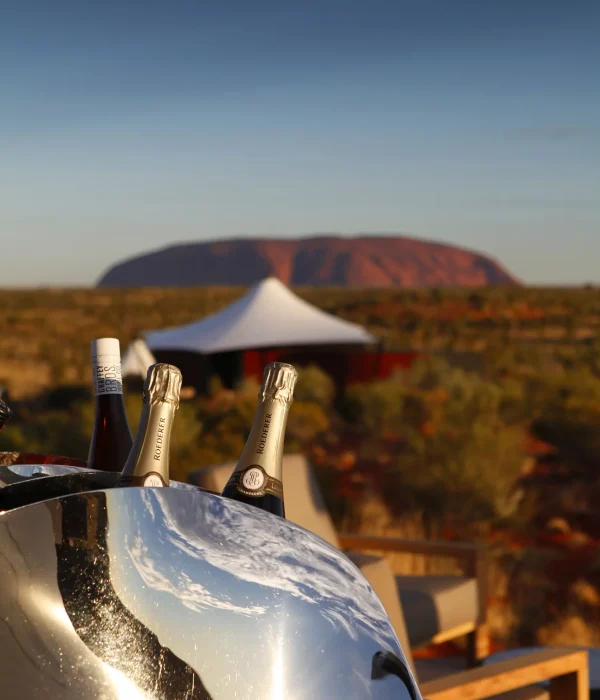 Bottles of champagne in a wine cooler overlooking Uluru in the Northern Territory